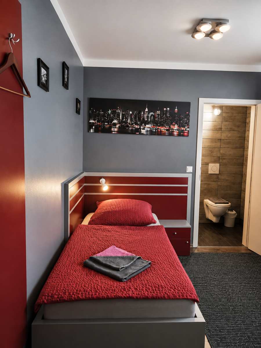 Einzelzimmer im Hotel 108 mit roter Tagesdecke und eigenem Bad