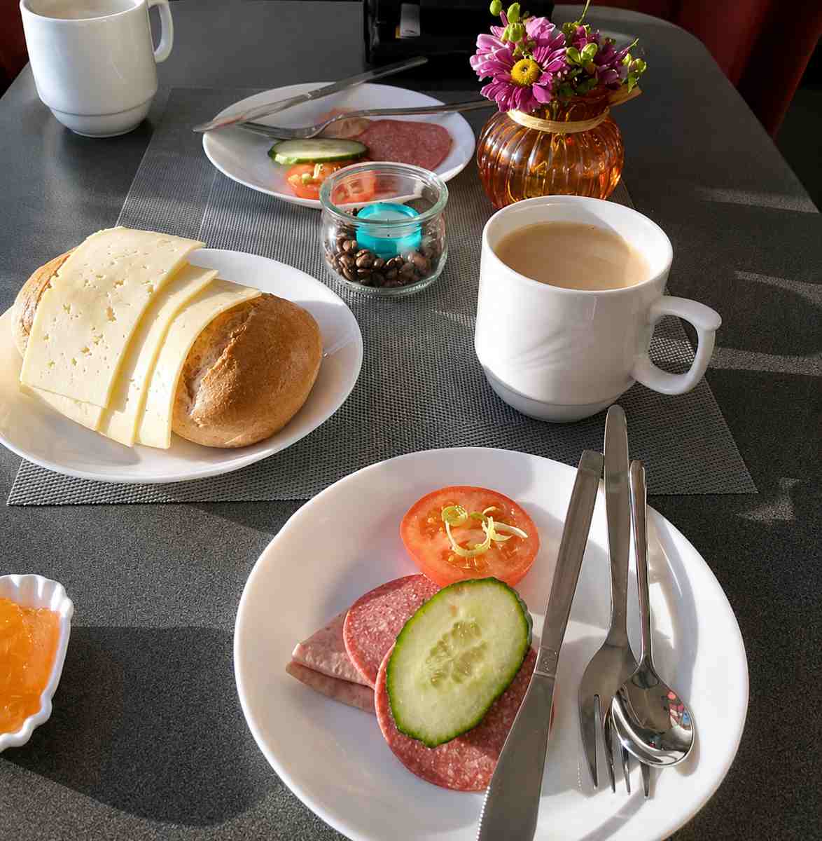 Gedeckter Frühstückstisch mit Kaffee, Brötchen, Käse und Aufschnitt im Frühstücksraum